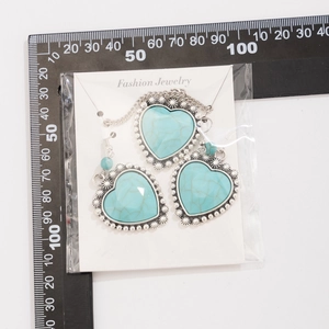 Flat lay detail of heart turquoise pendant and earrings set on white jewelry card