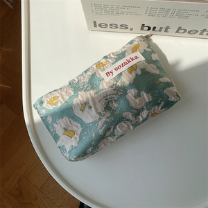 Close-up of mint green jacquard makeup bag with yellow floral texture and metal zipper