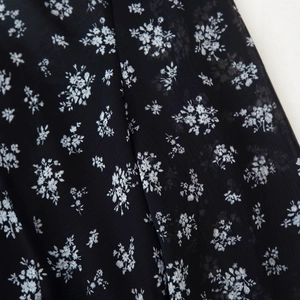 Nahaufnahme von schwarz-weißem Chiffonstoff mit Blumenmuster und eleganten Falten