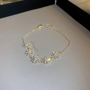 Detail of gold daisy bracelet featuring sparkling cubic zirconia flower charms on textured leather