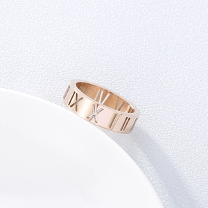 Close-up of rose gold titanium ring featuring hollowed Roman numeral cutouts on a white base