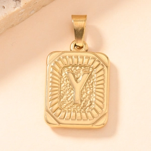 Macro shot of gold-plated rectangular pendant with engraved Y letter and hammered texture