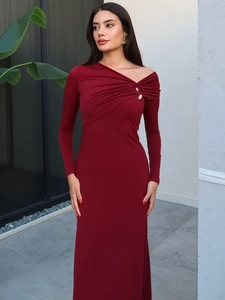 Detailed view of dark red knit dress with asymmetrical metal buckle and shoulder pleats