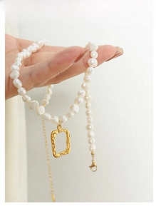Detail of freshwater pearl necklace featuring a textured gold rectangular pendant