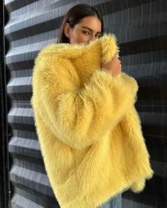 Detail shot of the thick yellow faux fur collar and plush texture on a luxury coat
