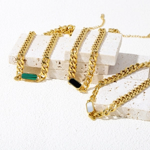 Detailed view of Cuban chain bracelets with green malachite and pearl shell inlays