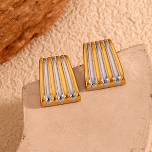 Détail macro de boucles d'oreilles trapézoïdales bicolores à rayures or et argent