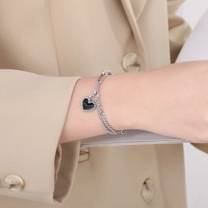 Detail of silver chain bracelet with black heart pendant and paperclip link design