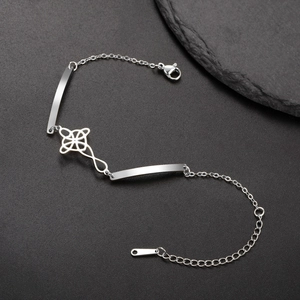 Macro detail of silver stainless steel bracelet featuring a central Celtic knot charm