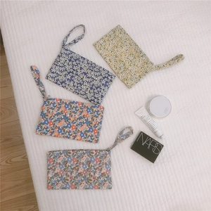 Dettaglio di quattro pochette in cotone a fiori con manici portatili e chiusure lampo