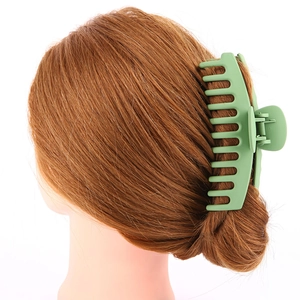 Detail view of a large light green hair claw clip styling long hair on a white background
