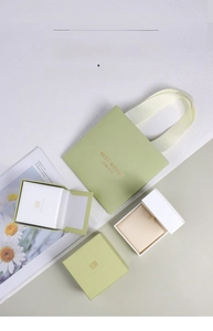 Detailed set of sage green jewelry gift boxes with gold handles on a marble surface