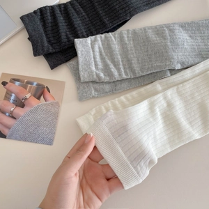 Détail de la texture côtelée et de l'élasticité des chaussettes en coton gris et beige