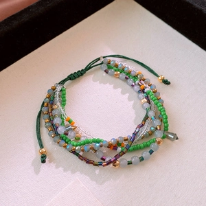 Detail of bohemian layered beaded bracelet with green cords and multicolor crystal beads