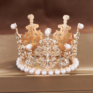 Close-up of golden alloy crown with white pearls and rhinestones on a metal stand