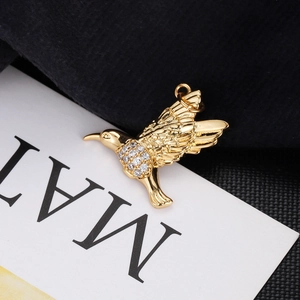 Macro shot of gold bird pendant with sparkling white zircons on delicate wing textures