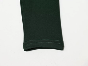 Detail of dark green knitted fabric showing high-density texture and double-needle stitching