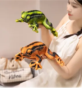 Detail of green and orange plush frogs held by a model in a cozy indoor setting