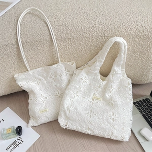 Détail de sacs fourre-tout en dentelle blanche brodée avec fleurs sur un canapé beige