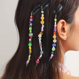 Close-up of colorful matte plastic beads with smiley and flower charms on dreadlock hair clips