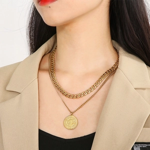 Close-up of golden layered chunky chain necklace featuring a vintage coin pendant