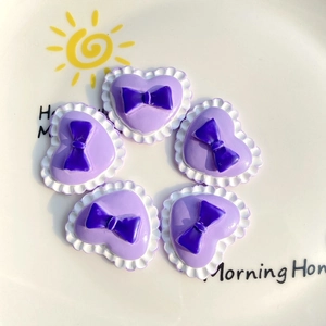 Detail of purple heart-shaped resin charms with bow ties for DIY phone case crafts