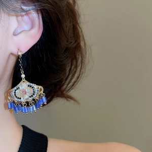 Détail de longues boucles d'oreilles bohèmes avec perles bleues et chaîne dorée
