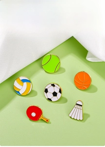 Detailansicht von sechs bunten Emaille-Anstecknadeln mit Sportmotiven wie Fußball und Basketball