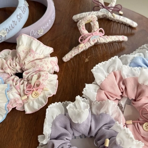 Detailsatz floraler Stoff-Haargummis und besticktem lavendelfarbenem Stirnband auf Holz