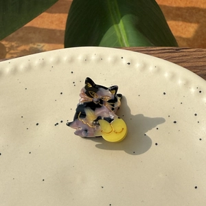 Close-up of a mini acetate cat hair clip with tortoiseshell pattern and gold details