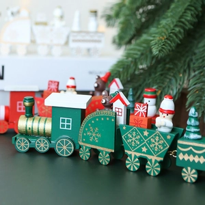 Green wooden Christmas train ornament with snowman and gift box miniatures on dark wood table