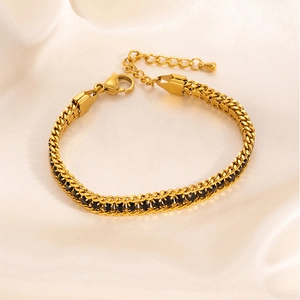 Detail of gold tennis bracelet with black cubic zirconia on white silk background