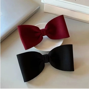 Detail of oversized bow hair clips in velvet red and black for elegant styling