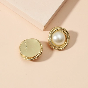 Elegant gold twisted rope stud earrings with baroque pearl center on peach background