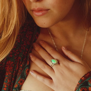 Gros plan d'une bague opale vintage et d'un collier en argent sur un mannequin bohème