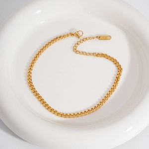 Detailed macro of gold Cuban link chain with extension and lobster clasp on a white plate