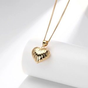 Detailed view of golden heart pendant necklace with elegant vertical shell textures