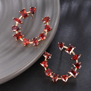 Detailed macro view of C-shaped gold earrings with red multi-shape zircon gemstones