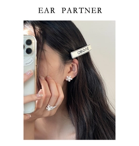 Close-up of floral pearl earrings and ring set worn for an elegant commute style