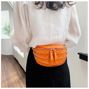 Detail of quilted orange chest bag featuring triple metal chains and dual zippers
