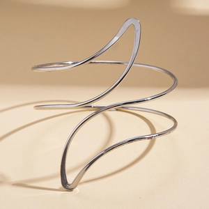 Detail of silver spiral arm cuff bracelet with sleek irregular curves and polished finish
