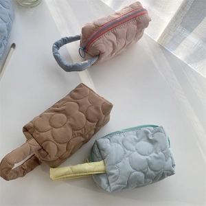 Detailed view of three quilted floral cosmetic bags in pink, brown, and light blue colors