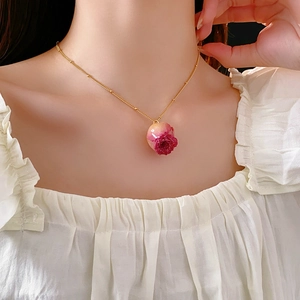 Close-up of elegant gold chain necklace featuring a pink and red gradient rose flower pendant