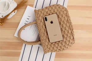 Straw woven handbag on a wooden desk with a coffee cup and magazine for a summer vibe
