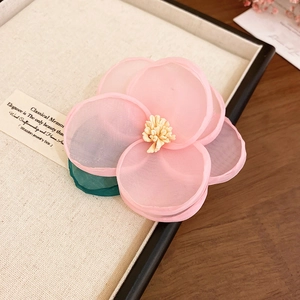 Detailed close-up of pink tulle flower hair clip with yellow pistils in a wooden jewelry box