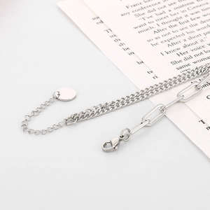 Détail d'un bracelet double couche argenté avec maillons mixtes et pendentif rond en métal