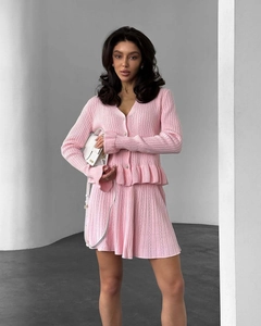 Détail d'un ensemble en maille rose avec cardigan à volants et jupe plissée à boutons diamants