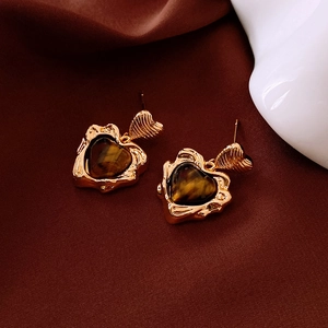 Détail macro de boucles d'oreilles cœur en oeil de tigre avec bordure dorée texturée