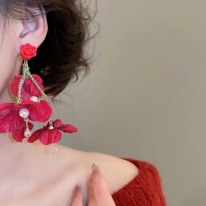 Macro shot of red fabric flower earrings with crystal tassels and faux pearls