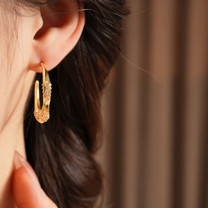 Dettaglio di orecchini a cerchio ritorto a C placcati oro 18K con pavé di zirconi luminosi